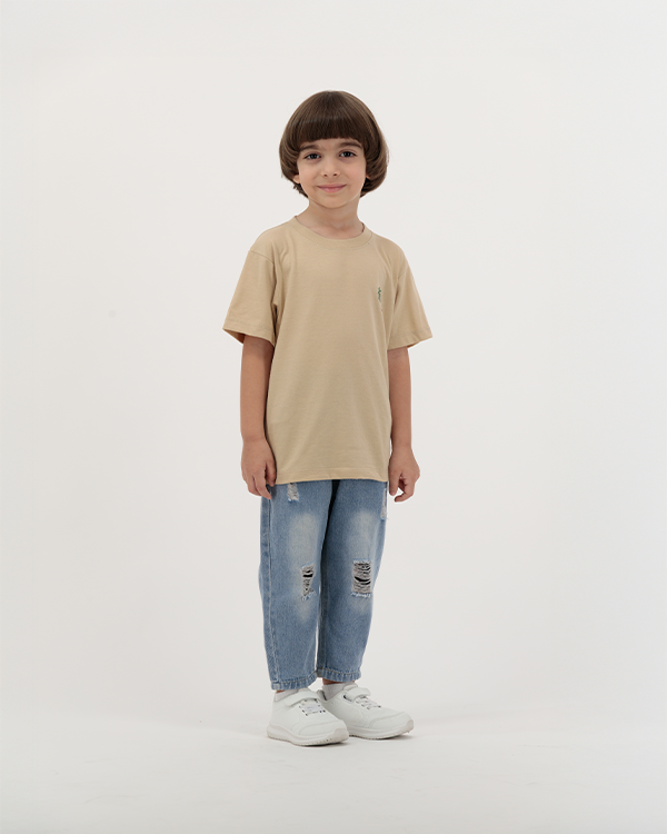 Boy modeling The Palm Kids T-Shirt with tropical leaf design.