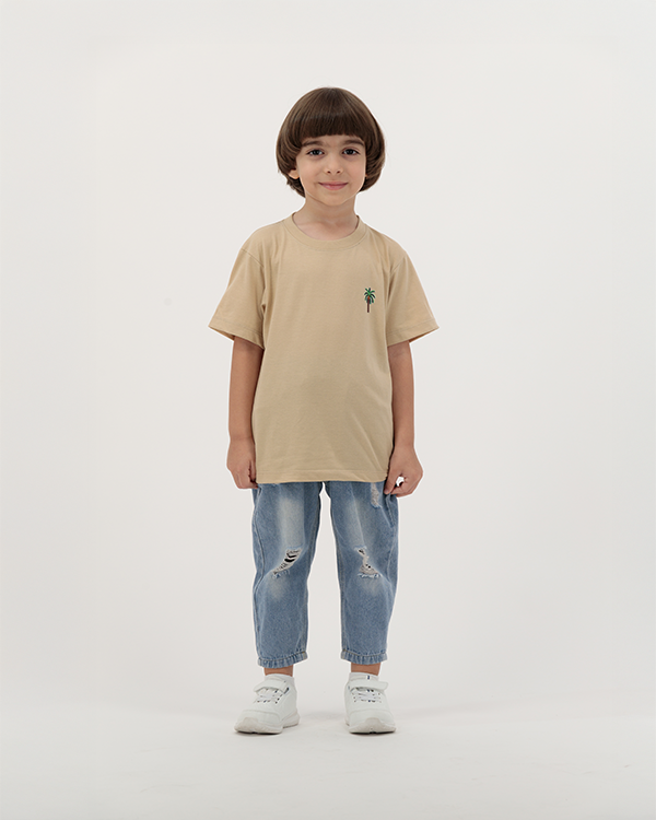 Young boy in The Palm Kids T-Shirt featuring tropical palm print.