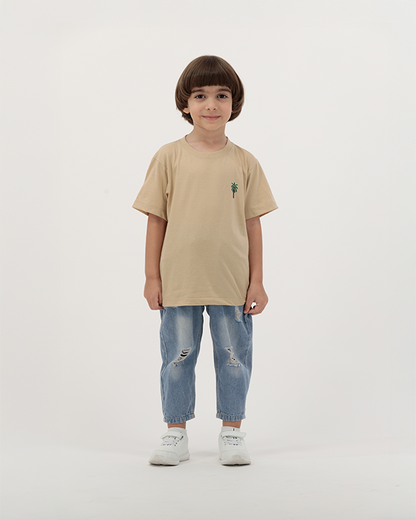 Young boy in The Palm Kids T-Shirt featuring tropical palm print.