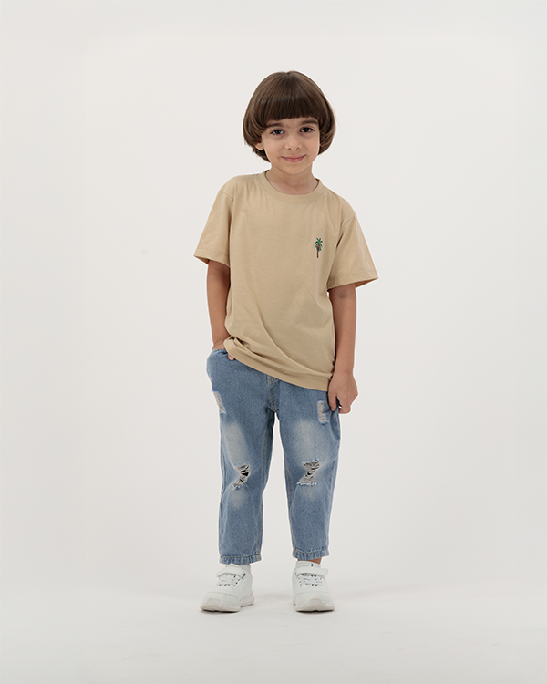 Child boy wearing beige palm tree print T-shirt from The Palm Kids collection.