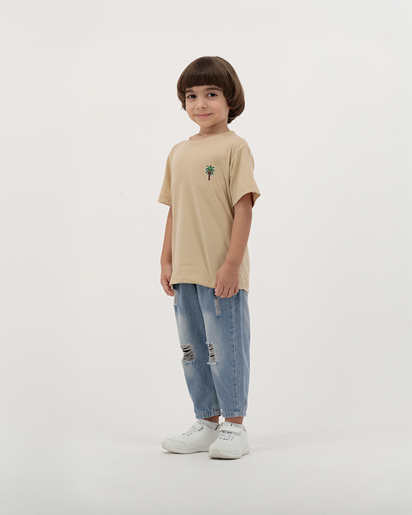 Kid wearing The Palm beige T-Shirt with palm tree graphic.