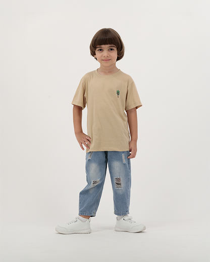 Boy in beige The Palm T-Shirt featuring palm trees and sun print.