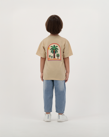 Child wearing The Palm Kids T-Shirt with palm leaf illustration.