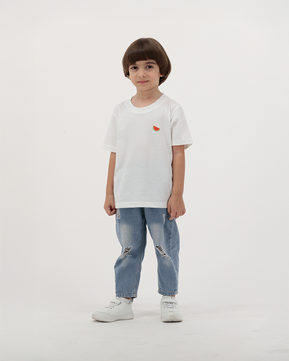 Young boy in Batikh Kids T-Shirt featuring colorful watermelon and fruit print.