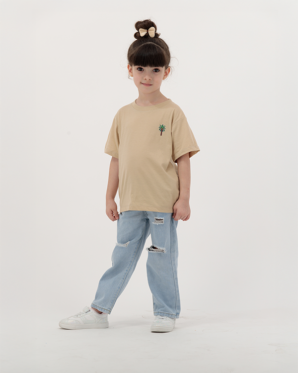 Young girl in The Palm Kids T-Shirt featuring palm tree artwork.
