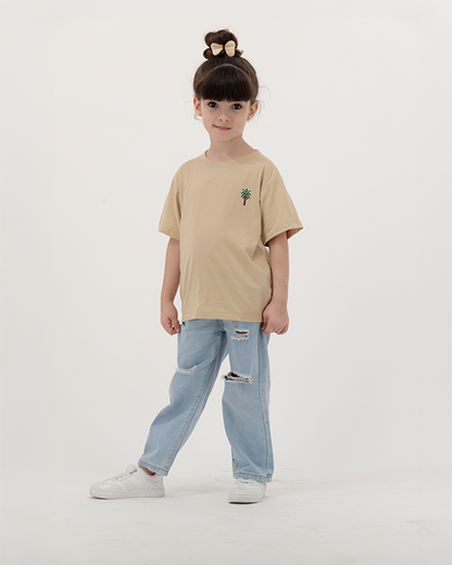 Young girl in The Palm Kids T-Shirt featuring palm tree artwork.