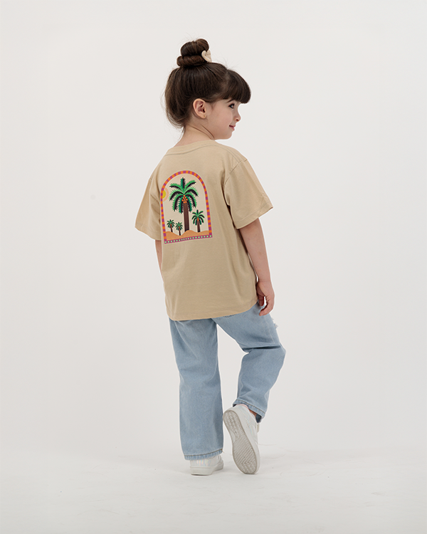 Girl dressed in The Palm Kids Leaf Print Tee with palm tree graphic.