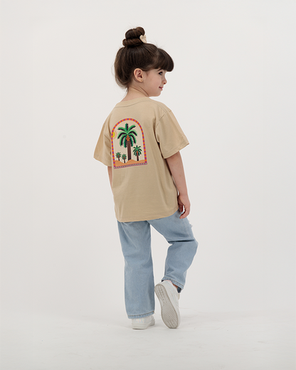 Girl dressed in The Palm Kids Leaf Print Tee with palm tree graphic.