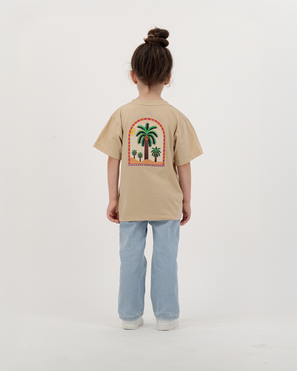 Girl modeling The Palm Kids beige T-Shirt featuring colorful palm print.