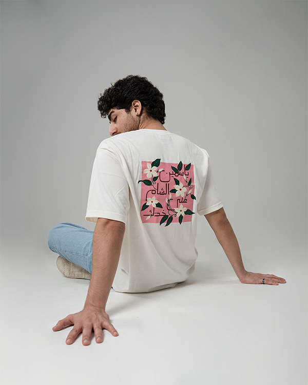 Man in white Jasmine Oversized T-Shirt with artistic floral back print.